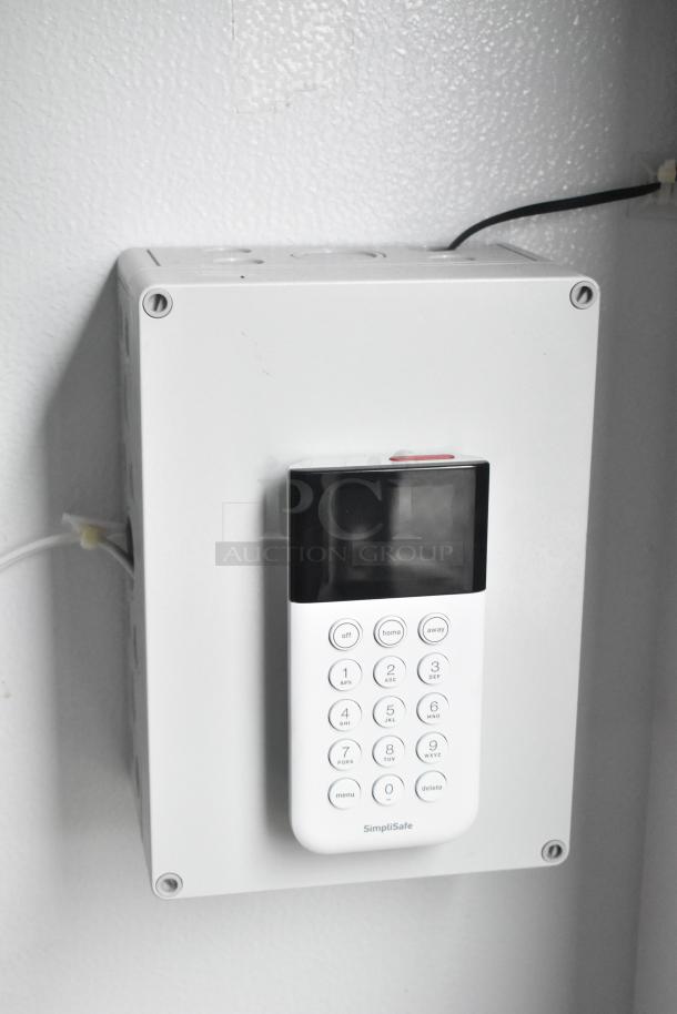 SimpliSafe keypad mounted on a wall, part of the SDG 8.5' x 20' food trailer shell. Key features include ready installation for security.