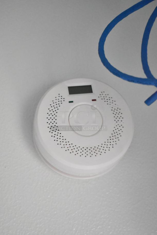 A smoke detector mounted on a ceiling with a digital display and LED indicators.