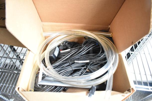 Box containing assorted cables and clear tubing, placed on a wire shelving unit.