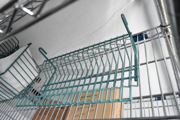 Metal wire shelving inside 2020 SDG 8.5' x 20' food trailer shell. Green hooks and cardboard box are visible on shelves.