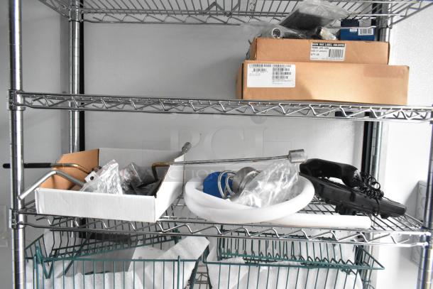 Metal wire shelving in SDG food trailer shell, holding cardboard boxes, plumbing parts, and a black phone handset.