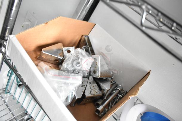 Box of hardware components including brackets and screws, intended for equipping a 2020 SDG 8.5' x 20' food trailer shell.