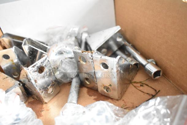 Box of metal fittings including brackets, hinges, and bolts, showing slight rust and wear in cardboard packaging.