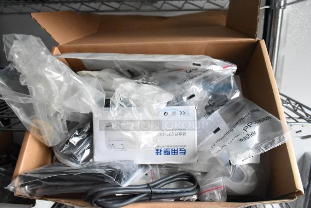 Cardboard box on a metal shelf containing various plastic bags with components, labeled with sizes and hardware instructions.