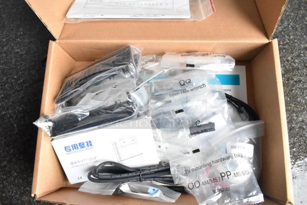 Box of TV mounting parts including hex wrench, bubble level, cables, and hardware bags labeled with sizes.