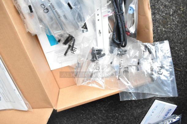 Cardboard box containing hardware for IT or network installation, including screws and cables in labeled plastic bags.