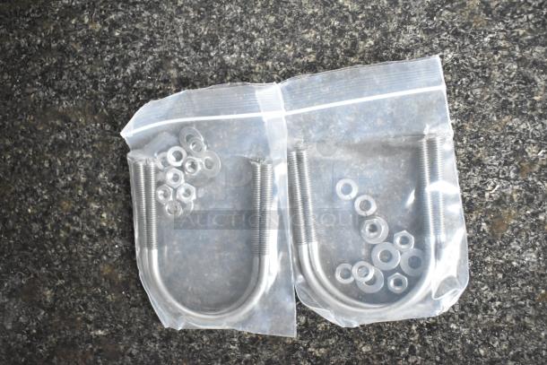 Two sealed bags containing U-bolts, washers, and nuts on a textured surface.