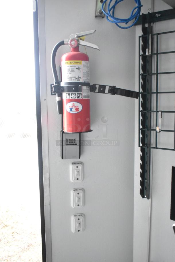 2020 SDG 8.5' x 20' food trailer interior; features fire extinguisher, wire shelving, light switches, ready for customization.