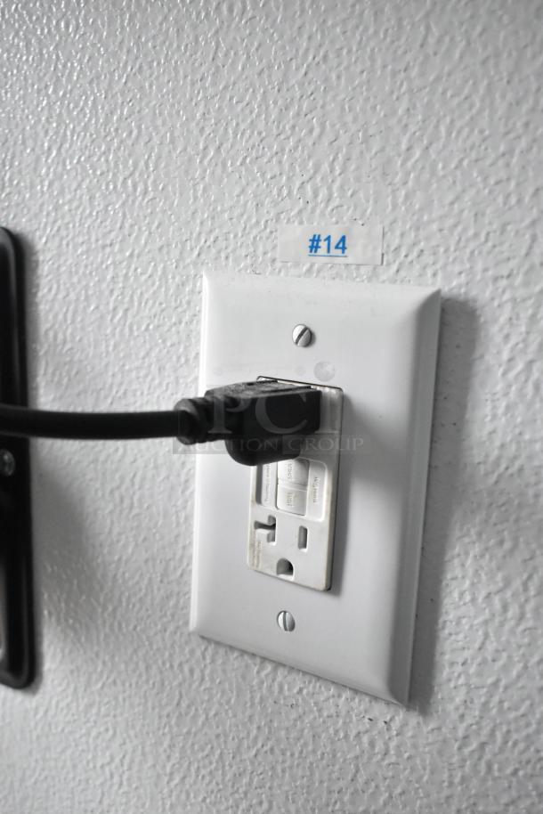 Electrical outlet close-up with cable plugged in, on textured wall labeled "#14".
