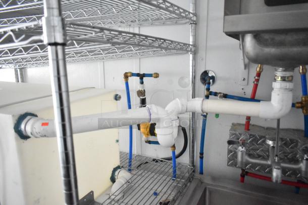 2020 SDG 8.5' x 20' food trailer shell interior; shows installed plumbing, wire shelving, and sink setup.