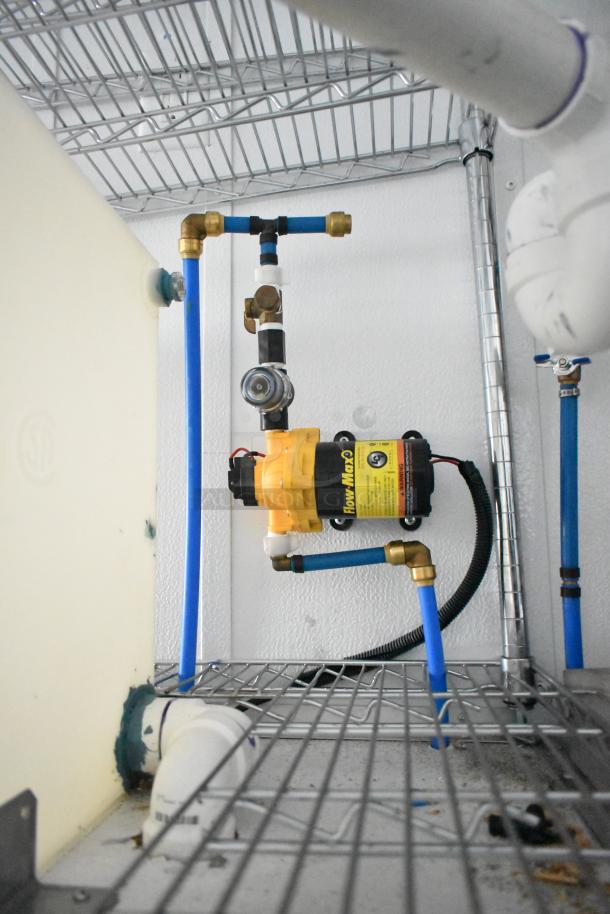 2020 SDG 8.5' x 20' food trailer shell interior showing Flow Max pump, wire shelving, plumbing setup; durable and ready for customization.