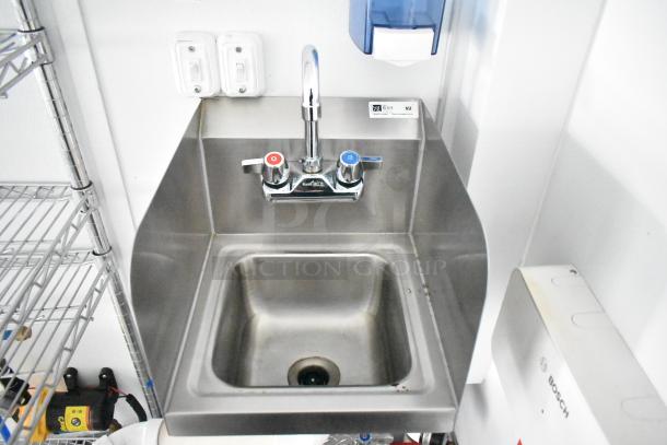 Stainless steel sink in a 2020 SDG 8.5' x 20' food trailer shell, featuring dual faucet handles and wire shelving.