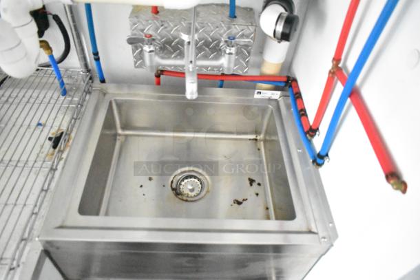 SDG food trailer interior showing stainless steel sink with faucet, wire shelving, and plumbing. Ready to equip. Clear title.
