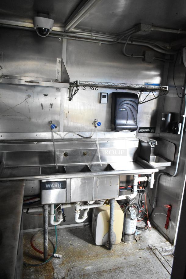 2019 Cruising Kitchens food trailer interior showing triple sink, CaptiveAire hood, shelving, and fire suppression system.