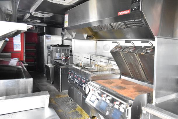 2021 Titanium Cargo 8.5' x 28' mobile kitchen trailer interior with Henny Penny fryer, Taylor soft serve, Garland griddle, and CaptiveAire hood.