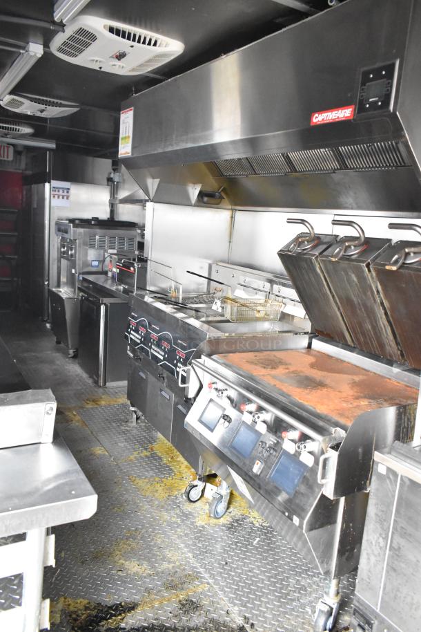 2021 Titanium Cargo 8.5' x 28' mobile kitchen with Henny Penny fryer, Taylor soft serve machine, Garland griddle, and CaptiveAire hood.
