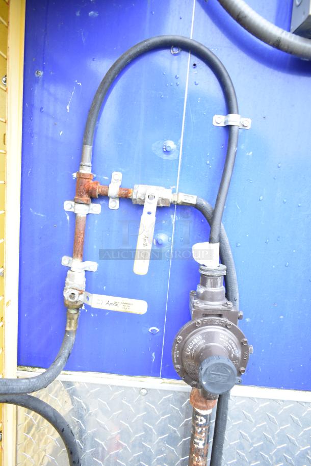 Mobile kitchen trailer utility panel with pipes, valves, and regulator. Visible labels: "Apollo" and "Resco".