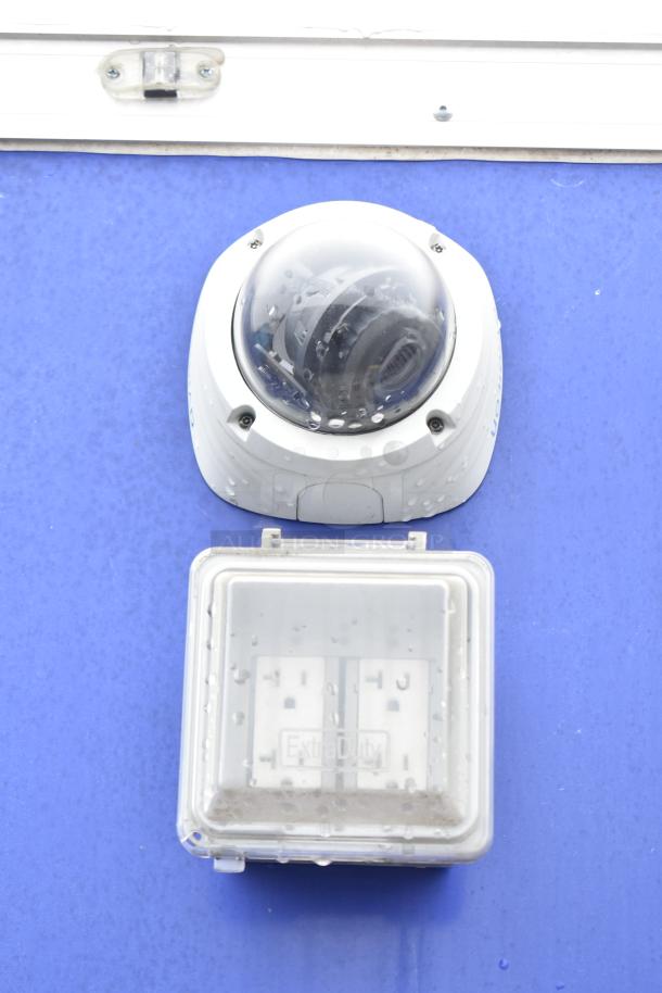 Security camera and electrical outlet on the exterior of a Burger King mobile kitchen trailer.