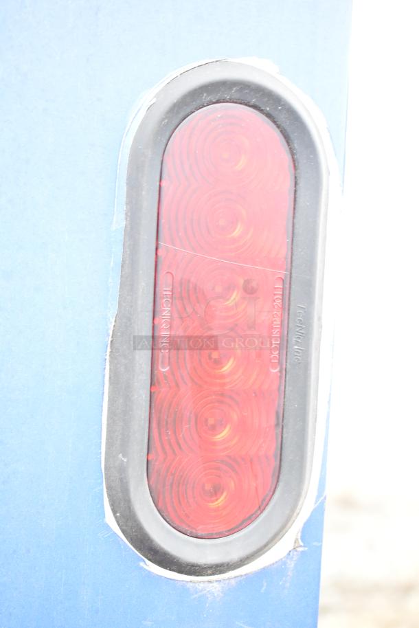 Red oval trailer light by TecNiq Inc., mounted on a blue surface.