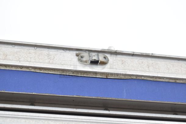 Mobile kitchen trailer detail showing secure latch on metal frame. Features CaptiveAire Hood, Pitco Fryers, and Arctic Air units.