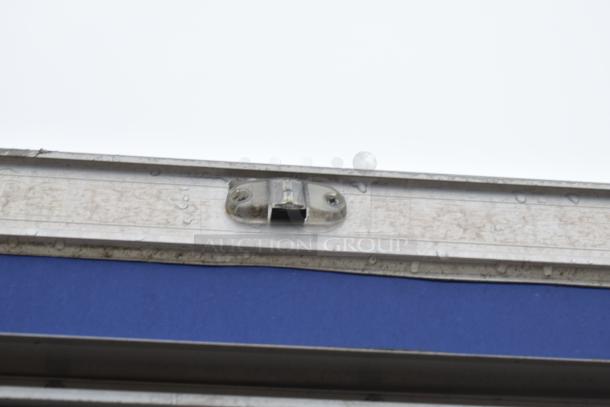 Metal latch on mobile kitchen trailer exterior, shows wear and water droplets. Part of fully outfitted trailer setup.