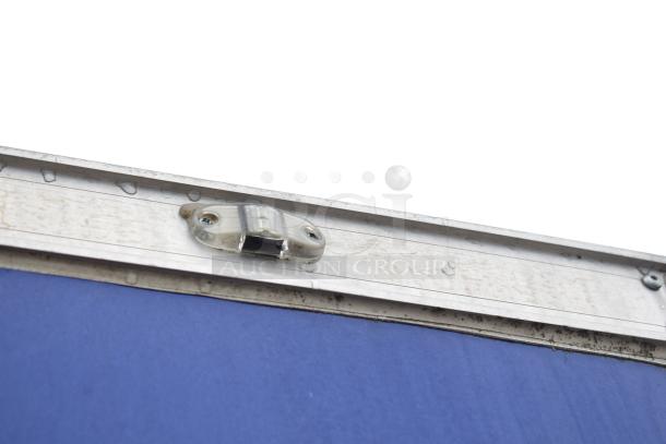 Close-up of mobile kitchen trailer's metal frame edge with visible wear, showcasing a latch mechanism.