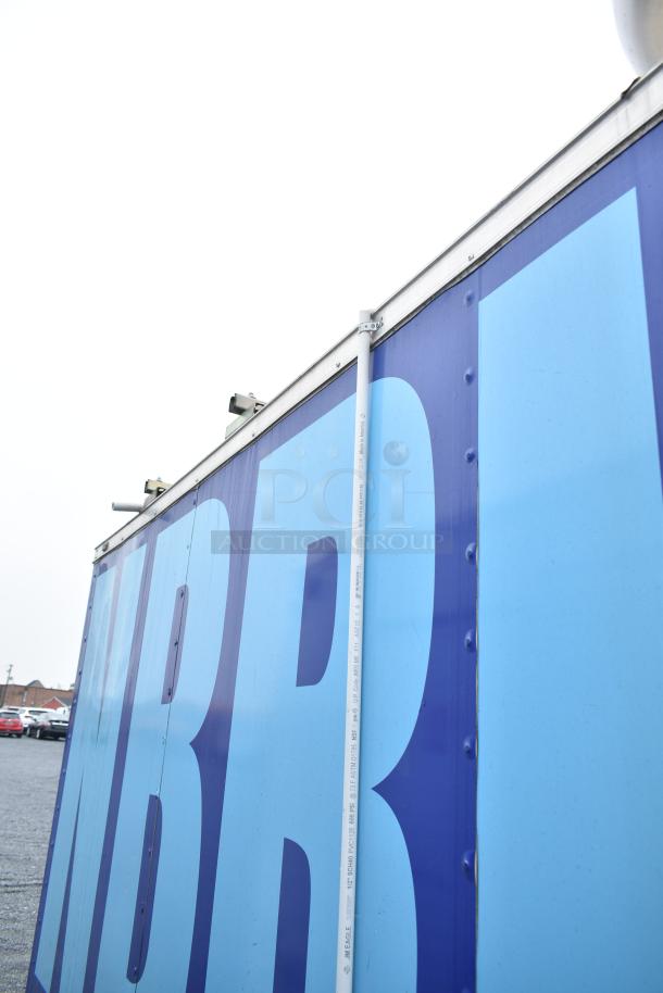 Exterior view of a mobile kitchen trailer, featuring side walls with bold blue lettering.