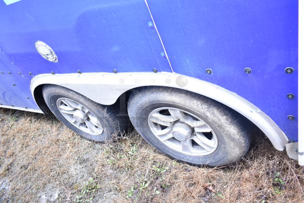 Blue mobile kitchen trailer side view with dual rear wheels, showing part of its exterior condition and hardware elements.