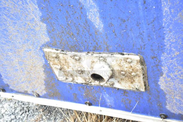 Exterior detail of a mobile kitchen trailer, blue surface with visible rust and piping, showing signs of wear.