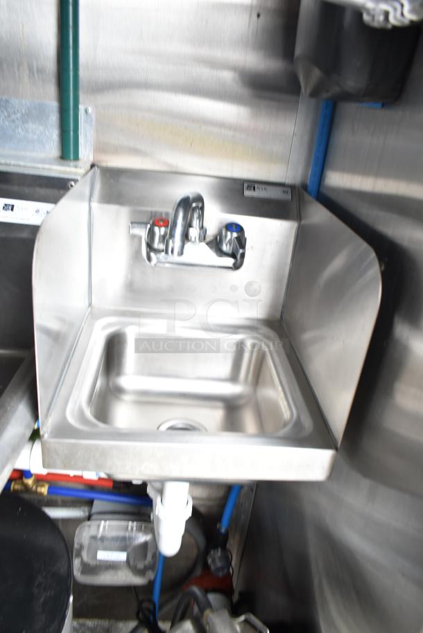 Stainless steel sink with dual faucets in mobile kitchen trailer. Features include CaptiveAire hood and Arctic Air equipment.