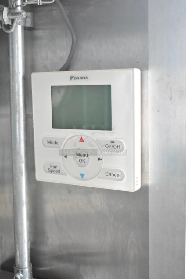 Daikin air conditioning control panel inside mobile kitchen trailer, featuring menu, mode, and fan speed buttons.
