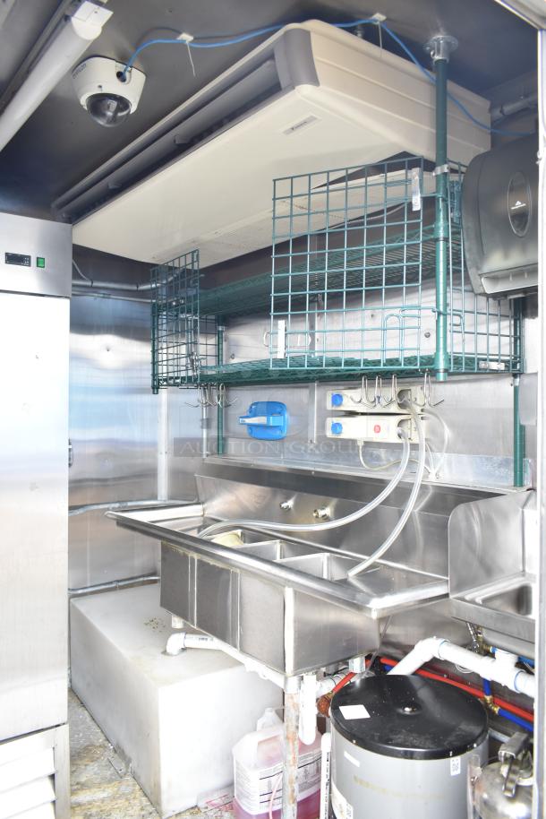 Mobile kitchen trailer interior with CaptiveAire hood, Arctic Air prep tables, dual sink, and air conditioning unit.