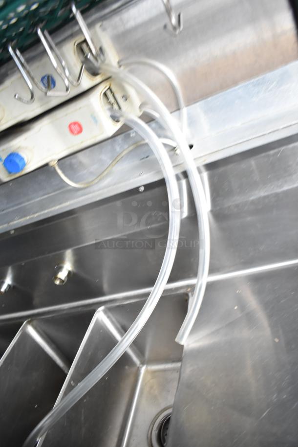 Mobile kitchen trailer sink with plumbing hoses. Stainless steel finish, part of a fully equipped setup.