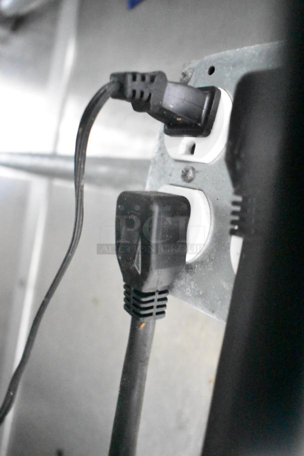 Electrical outlet with plugged-in cables inside a mobile kitchen trailer, part of full POS infrastructure.