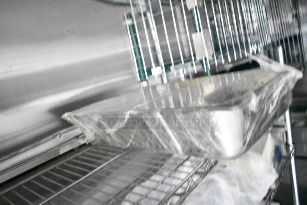 Mobile kitchen trailer interior; features metal shelving, covered trays, and visible stainless steel elements.