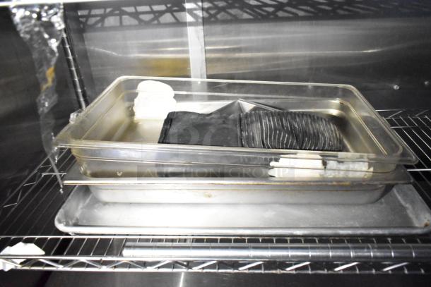 Stainless steel shelving with stacked rectangular food trays in a mobile kitchen trailer interior.