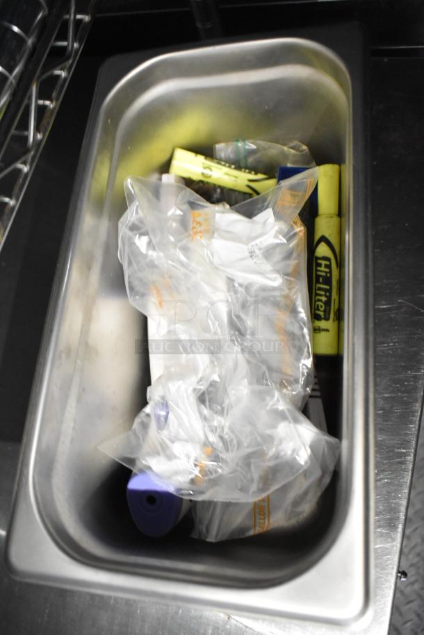 Stainless steel kitchen sink with various highlighters and plastic bags, part of a mobile kitchen trailer's interior.