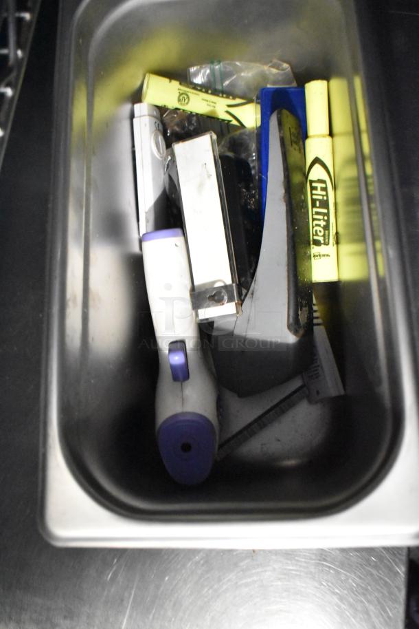 Tray with assorted tools and highlighters, including a Hi-Liter brand pen and white utility tool with purple button.