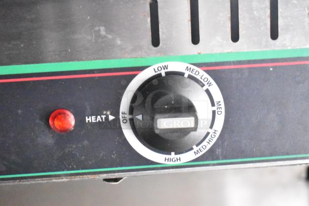 Control knob of a mobile kitchen trailer appliance, showing heat settings from low to high, with red indicator light.