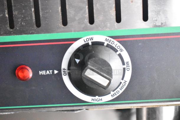 Control knob and heat indicator on a mobile kitchen trailer component, showing temperature settings from low to high.