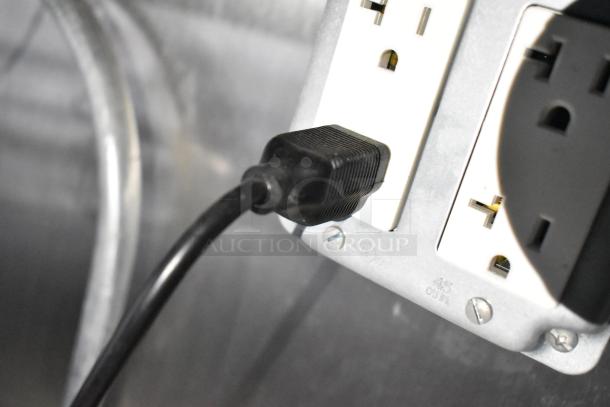 Close-up of an electrical outlet with a black plug inserted, part of a mobile kitchen trailer.
