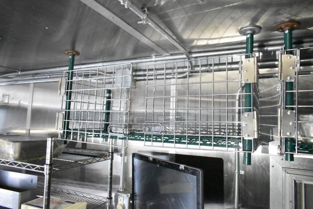 Mobile kitchen trailer interior with stainless steel CaptiveAire hood, Arctic Air prep table, metal shelving, and POS system.