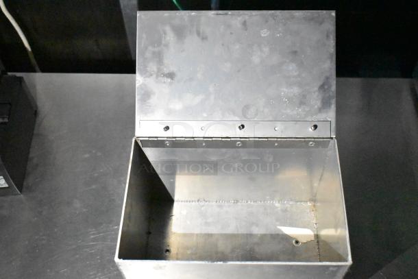 Steel container with hinged lid, showing interior, possibly kitchen-related. No visible labels or markings.