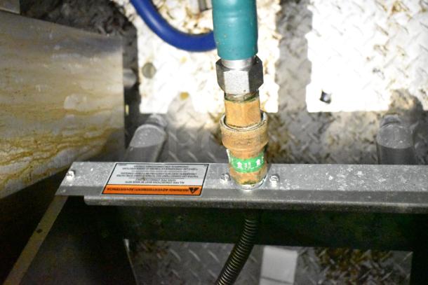 Gas connection in mobile kitchen trailer, featuring a safety label. Part of a fully outfitted kitchen setup.