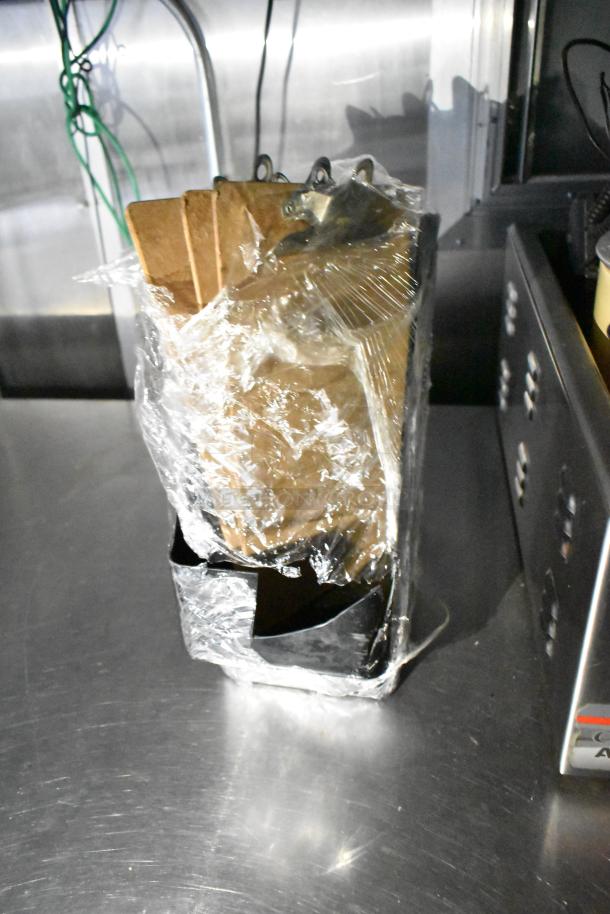 Alt text: Inside view of a mobile kitchen trailer with CaptiveAire hood, Pitco fryers, and Arctic Air prep tables. Plastic-wrapped tray on a metal surface.