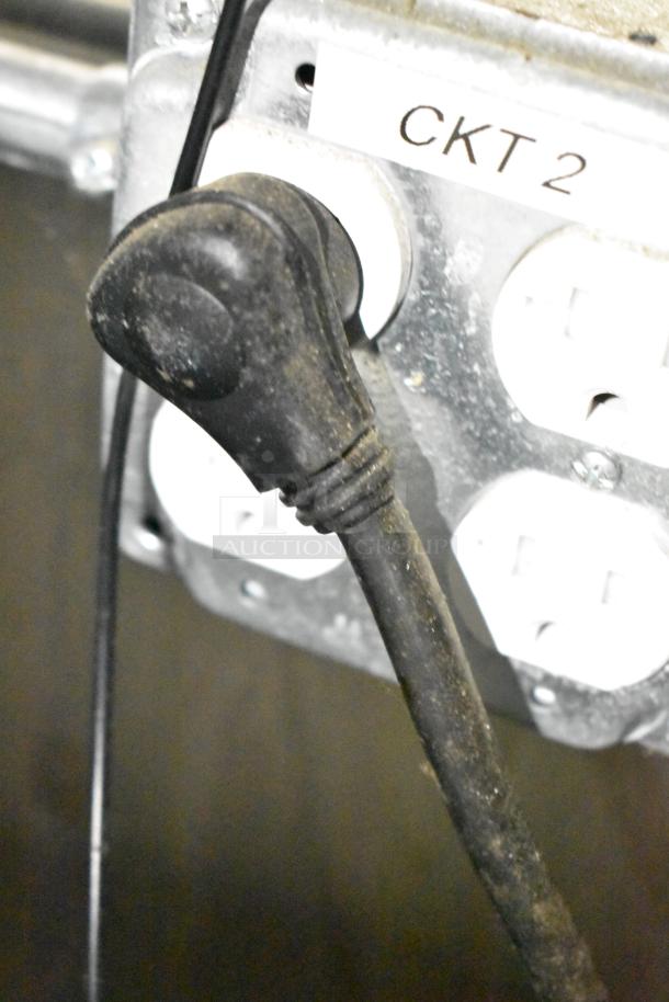 Power outlet labeled "CKT 2" with a plugged-in black electrical cord in the mobile kitchen trailer.