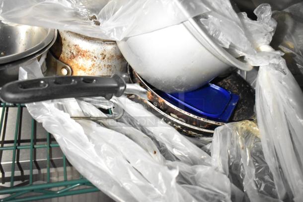Piles of cookware, pans, and utensils wrapped in plastic, indicating storage or transport.