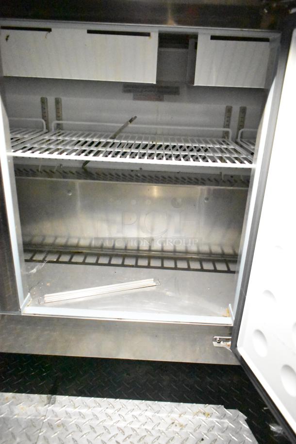 Inside view of Arctic Air cooler from a mobile kitchen trailer, showing metal shelving and interior space, suitable for food storage.