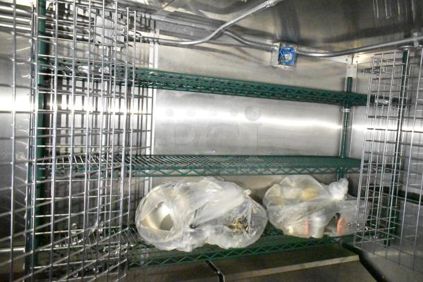 Mobile kitchen trailer shelving; metal racks with wrapped items. Interior view, clean and spacious.