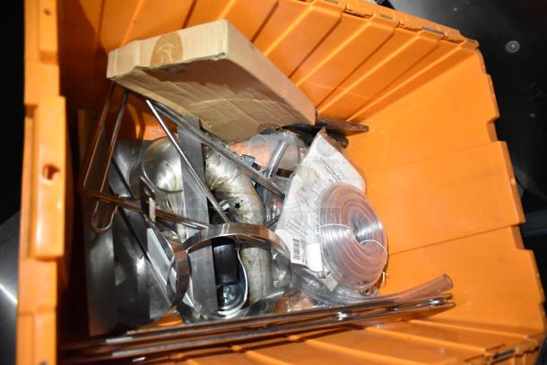 Orange bin with assorted kitchen trailer hardware, including metal brackets, plastic tubing, and cardboard. Suitable for setup or repairs.
